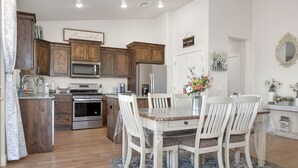 A kitchen with wooden cabinets, stainless steel appliances, and a dining area with a table and chairs.