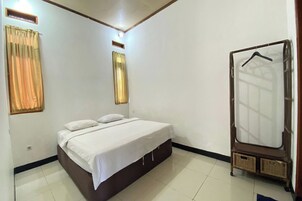 Un dormitorio con una cama individual, un armario y una ventana con cortinas.