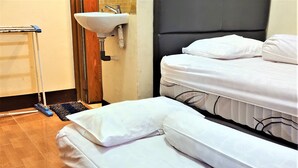 A hotel room with two beds, a bathroom with a sink and a mop, and a wooden floor. - Katawa Guest House Syariah (Palembang)