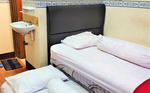 A small, clean room with a single bed, a bedside table, and a sink.