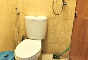 A bathroom with a toilet, shower, and a broom.