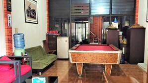 A pool table in a room with a sofa, a water dispenser, and a refrigerator. - Katawa Guest House Syariah (Palembang)
