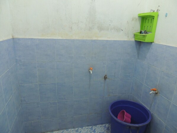 A bathroom with blue tiles, a green wastebasket, and a purple bucket. - Wisma Artha (Ngaglik)