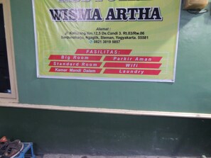 A signboard with the name 'WISMA ARTHA' and a list of amenities including Big Room, Standard Room, Parkir Aman, Wifi, and Laundry. - Wisma Artha (Ngaglik)