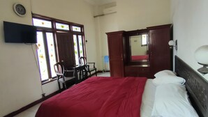 Une chambre à coucher avec un lit, un bureau et une chaise. Il y a une fenêtre donnant sur l’extérieur.