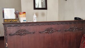 Un comptoir d’accueil avec une pancarte indiquant « RÉCEPTION », un certificat encadré, un flacon de gel hydroalcoolique et un téléphone.