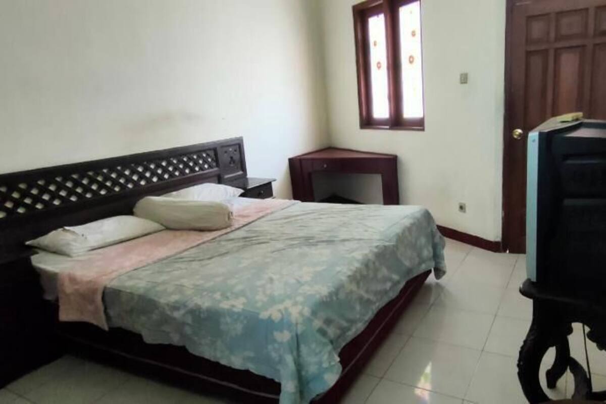 Une chambre à coucher comprenant un lit, une table de chevet, un bureau, une chaise et un téléviseur.