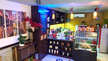 A cafe with a counter, seating area, and a display of snacks and drinks.
