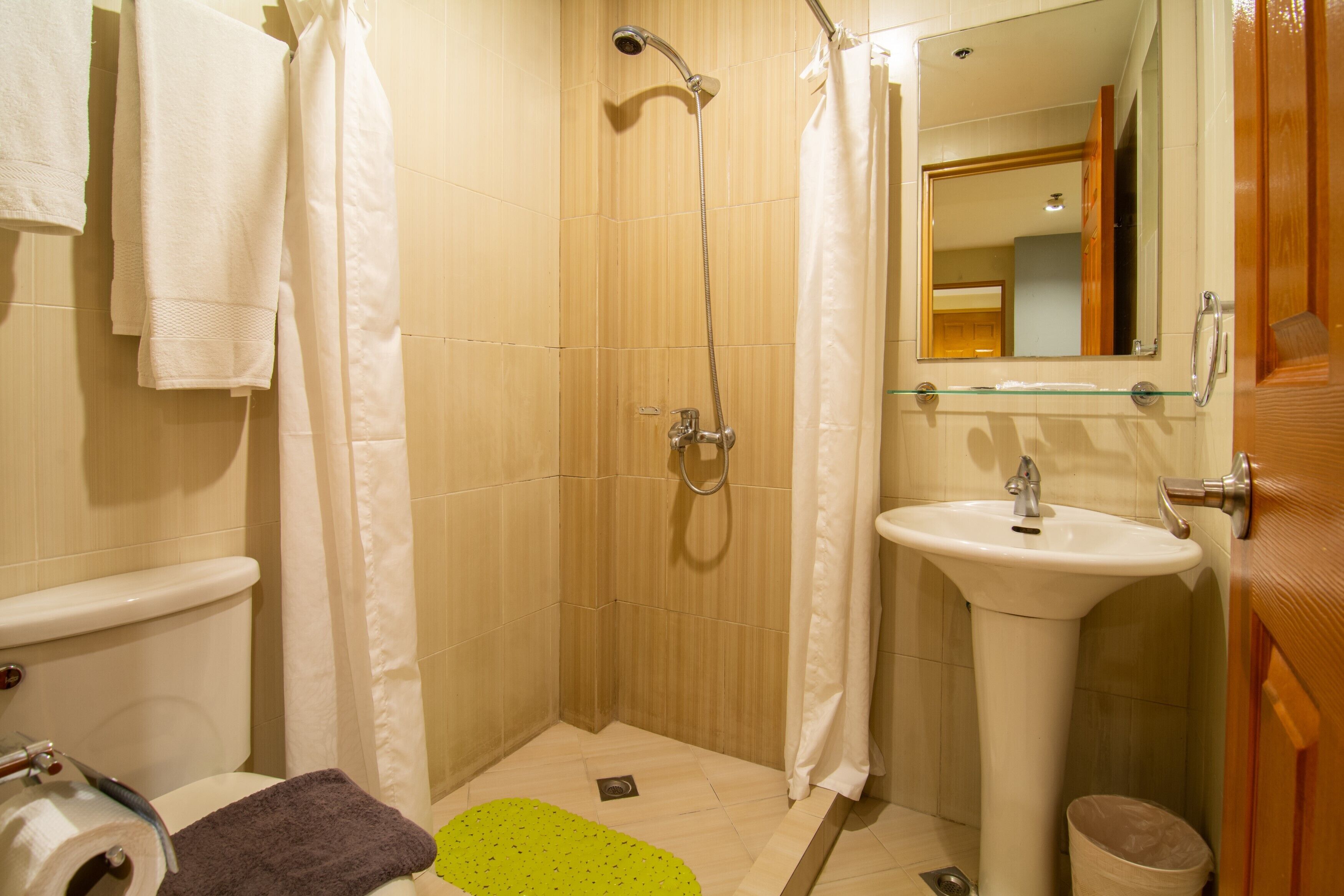 A bathroom with a shower, toilet, sink, and a mirror.