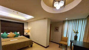 A hotel room with a bed, a desk, a chair, a lamp, and a ceiling light. - Festive Hotel Makati (Makati)