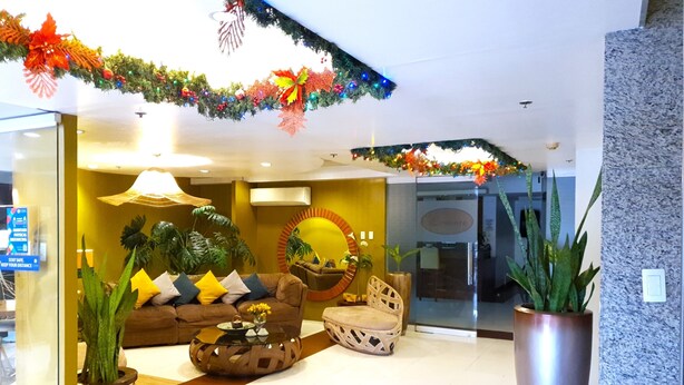 A lobby with a sofa, chairs, a coffee table, and potted plants. - Festive Hotel Makati (Makati)