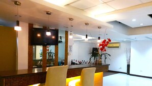 A modern bar area with two bar stools, a flat-screen TV mounted on the wall, and a sign prohibiting drinking and driving. - Festive Hotel Makati (Makati)