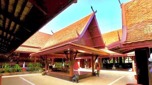 Um edifício tradicional tailandês com um pátio coberto, pilares de madeira e telhado de telhas.