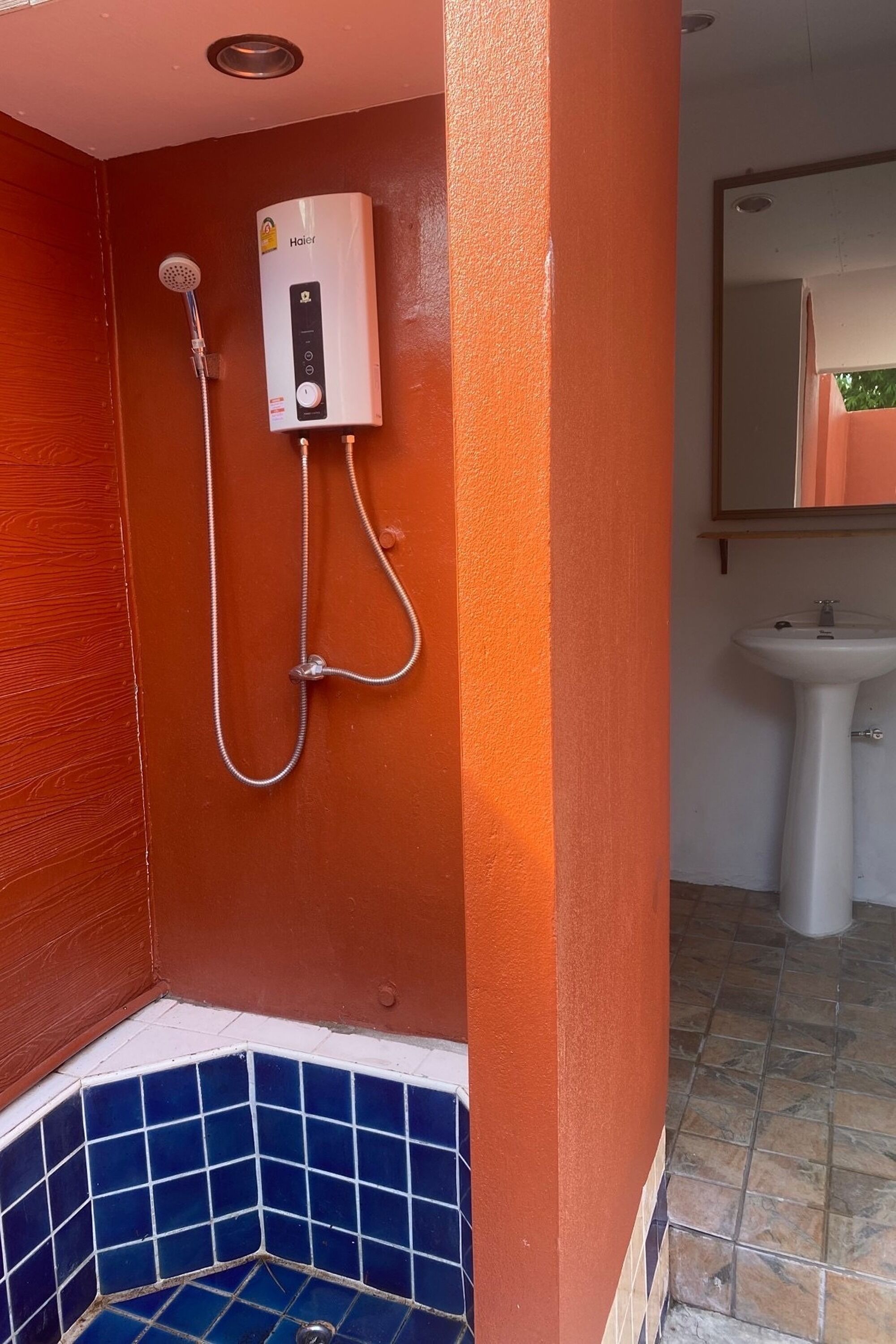 Un baño con cabina de ducha blanca, zona de ducha con azulejos azules y un lavamanos blanco.