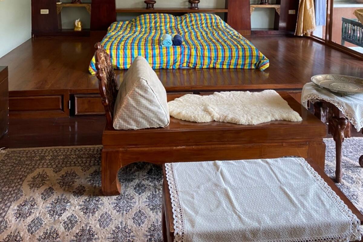 A bedroom with a large bed, wooden headboard, and a decorative wall hanging.