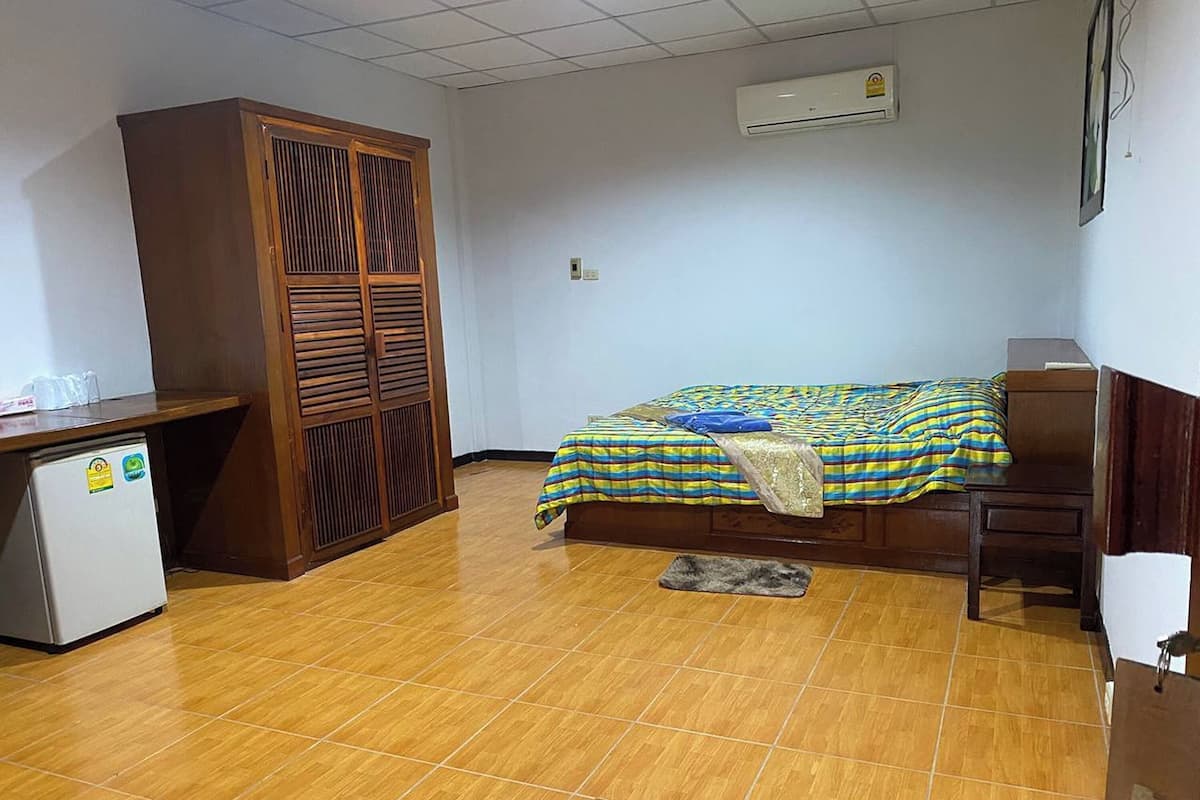 A room with a bed, a desk, a wardrobe, and an air conditioner.