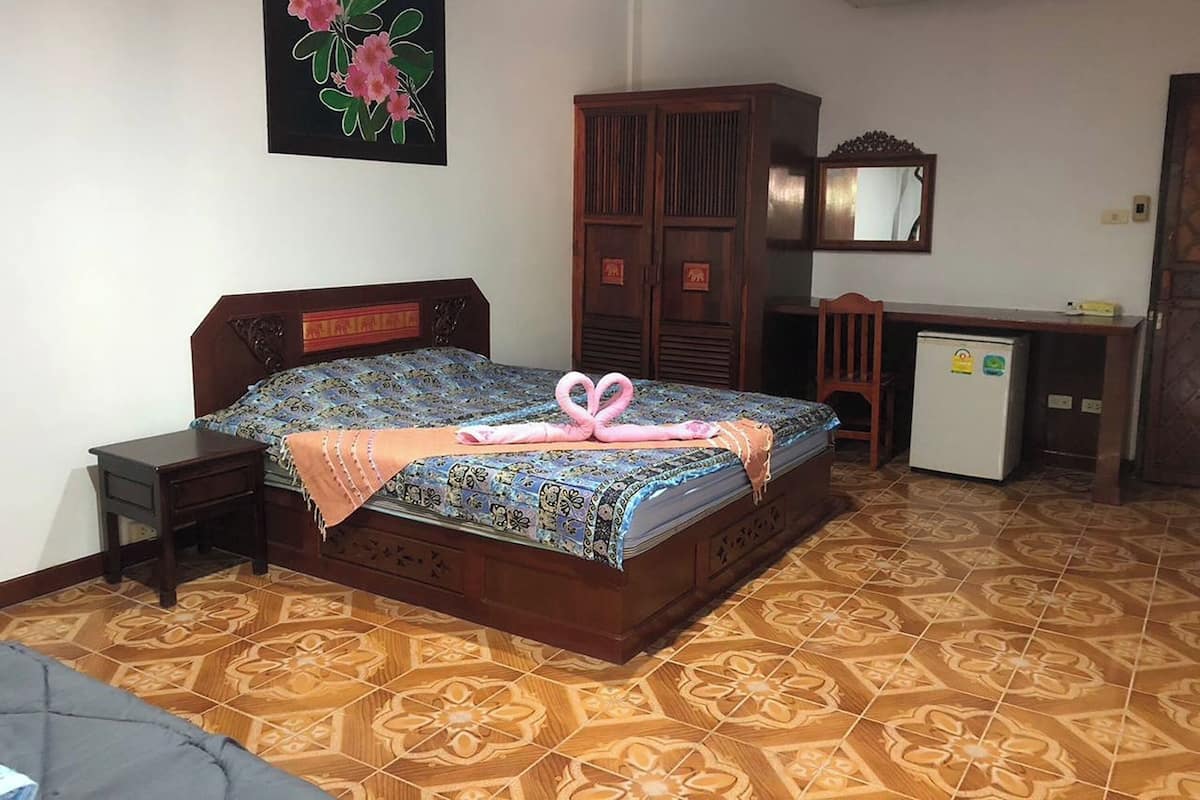 A bedroom with a bed, a desk, a wardrobe, and a refrigerator.
