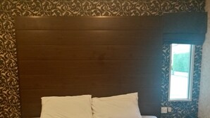 A room with a large bed, two pillows, a headboard, patterned wallpaper, and a window with a view. - The 9 Resort (Bangkok)