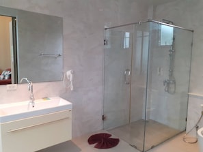 A modern bathroom with a glass-enclosed shower, a white sink, and a large mirror. - Areeca Mahogany Zone (Choeng Thale)