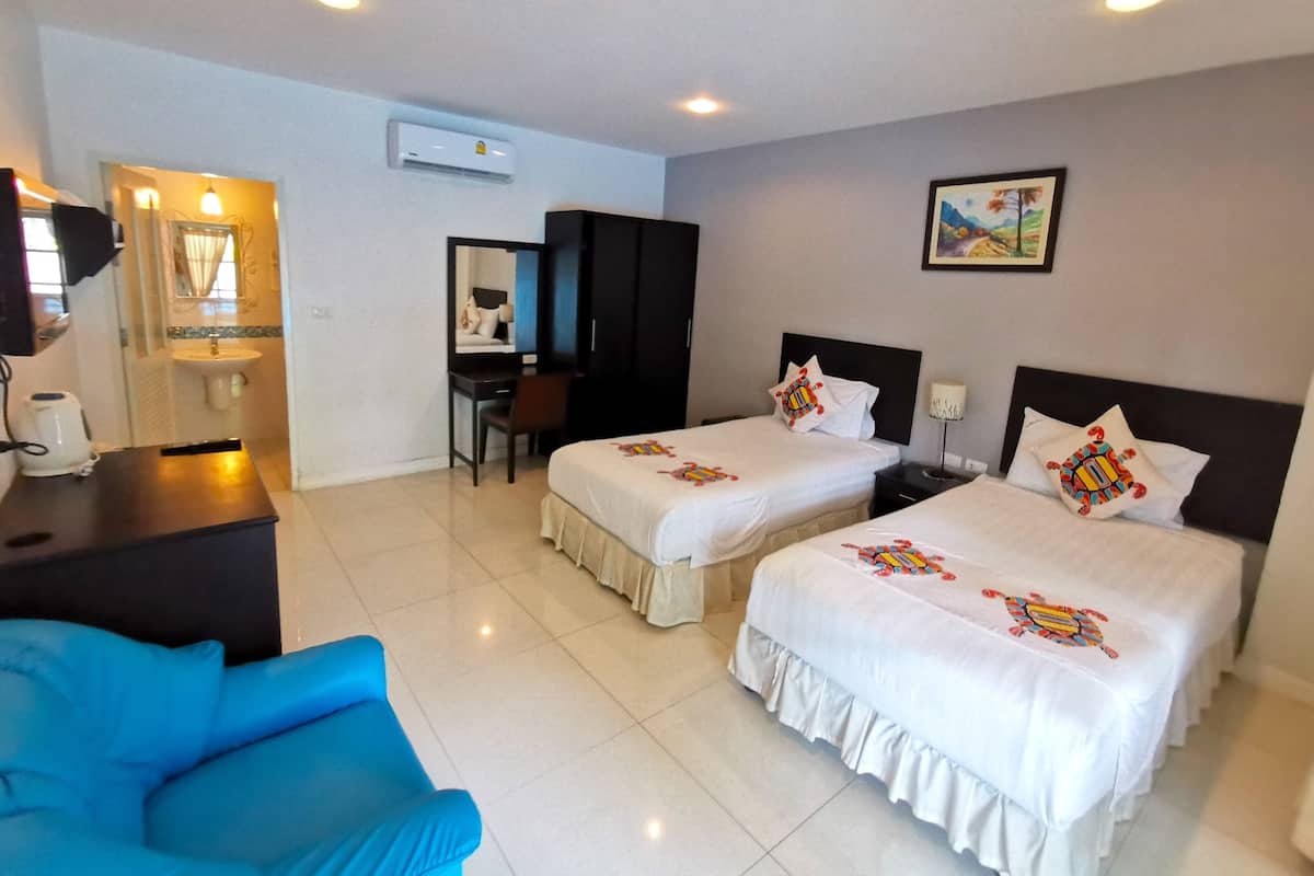 A hotel room with two beds, a desk, a chair, a sink, and an air conditioning unit.