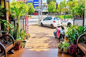 A street view with a white car parked in front of a building with a signboard. - T2B Hostel (Chiang Mai)