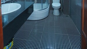 Un baño con ducha envuelta en vidrio, un lavamanos blanco y un inodoro.