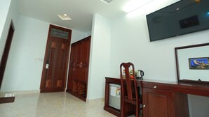 Un pasillo con una puerta de madera, un televisor montado en la pared y un cuadro enmarcado.