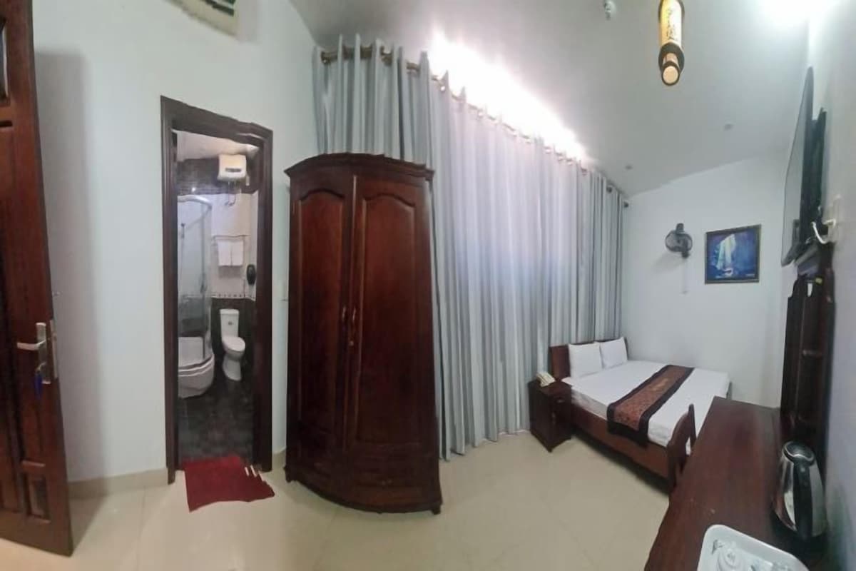 Ein Hotelzimmer mit Bett, Schrank und einem durchgegangenen Tür angedeuteten Badezimmer.