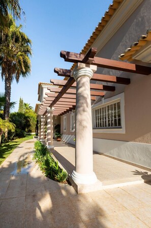 A building with a covered walkway, columns, and a tiled floor.