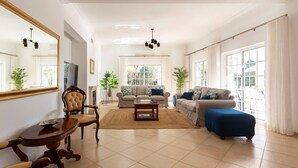 A spacious living room with a large mirror, two sofas, a coffee table, and a dining area with a wooden table and chairs. - Luxury Villa Jose with swimming pool (Quarteira)