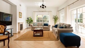 A living room with a fireplace, two sofas, a coffee table, and a TV. - Luxury Villa Jose with swimming pool (Quarteira)