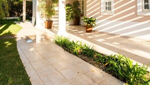 A two-story house with a covered patio, potted plants, and a well-maintained lawn. - Luxury Villa Jose with swimming pool (Quarteira)