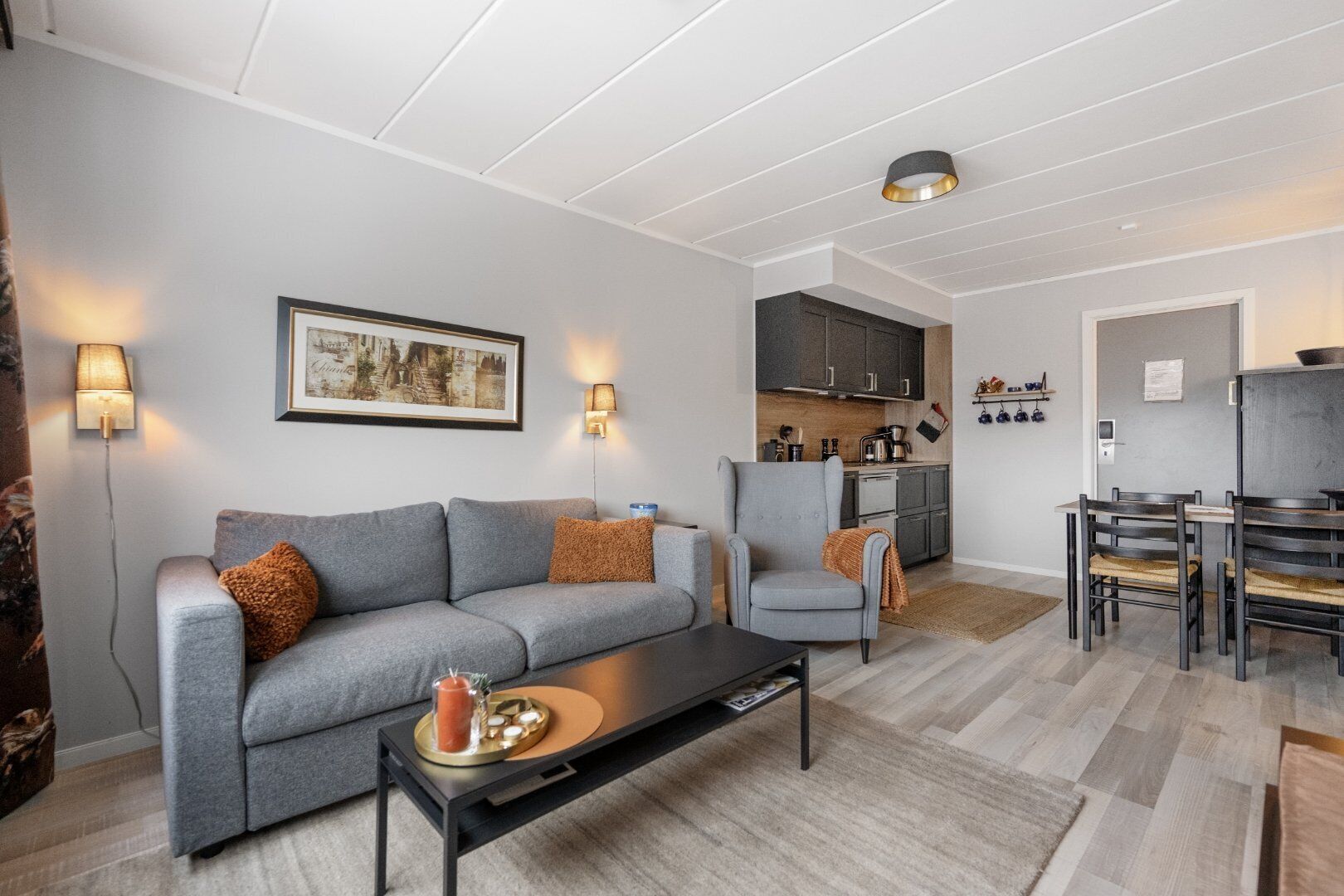 Una sala de estar moderna con un sofá gris, una mesa de centro y un comedor con sillas y una mesa.