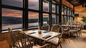 A dining area with large windows offering a view of a lake and mountains. - Spåtind Fjellhotell (Nordre Land)