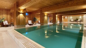 An indoor swimming pool with wooden walls and ceiling, surrounded by lounge chairs and potted plants. - Spåtind Fjellhotell (Nordre Land)