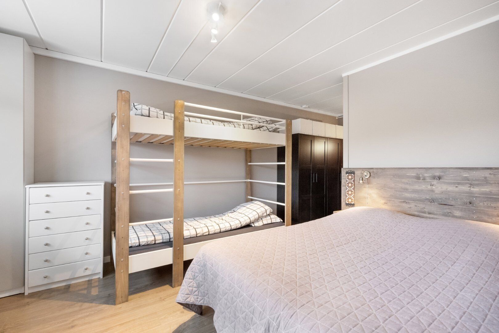 Ein Schlafzimmer mit Etagenbett, Holzrahmen, weißem Schminktisch und Kleiderschrank.