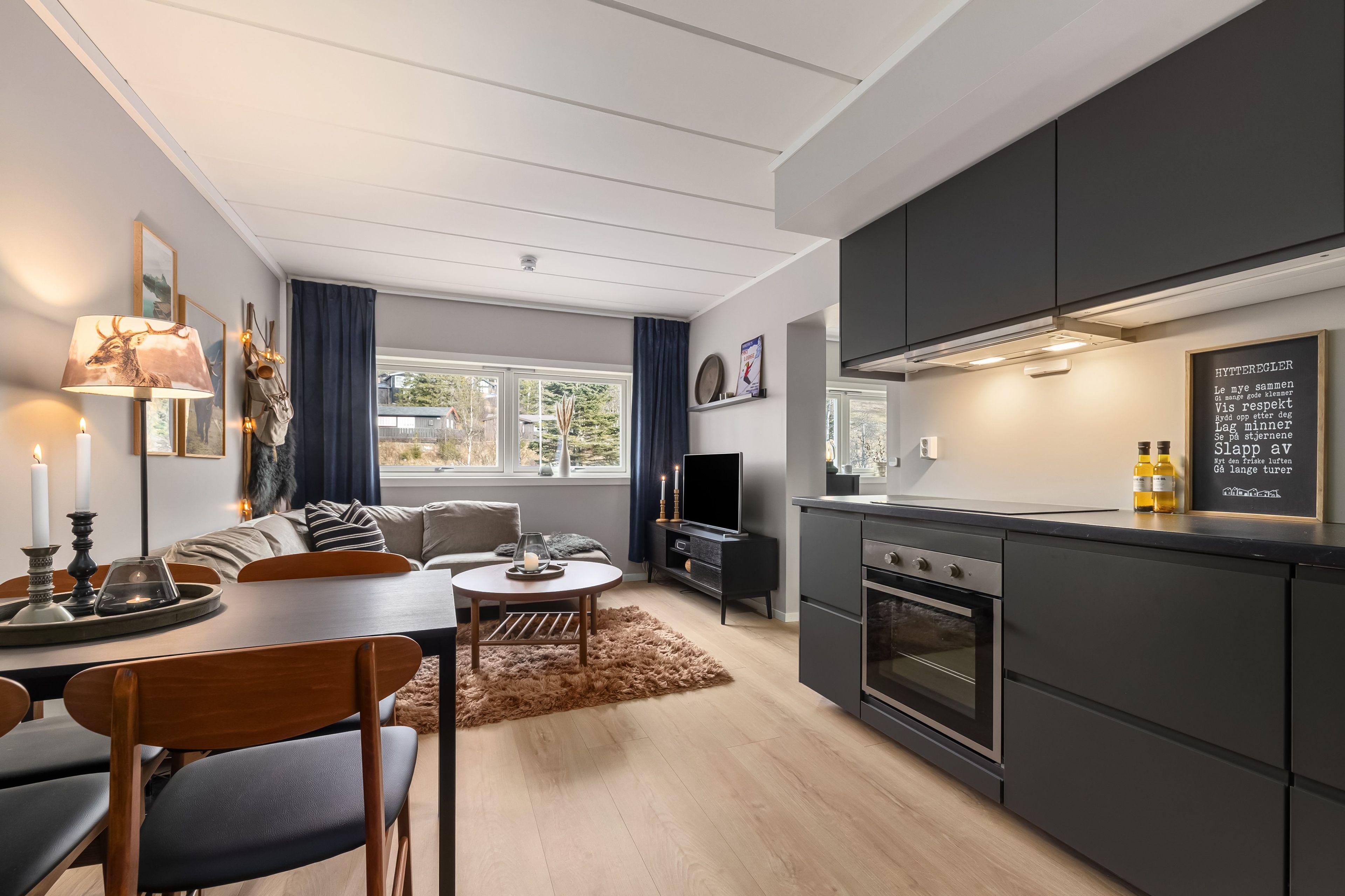 Een moderne keuken met een inbouwoven en een eethoek met een tafel en stoelen.