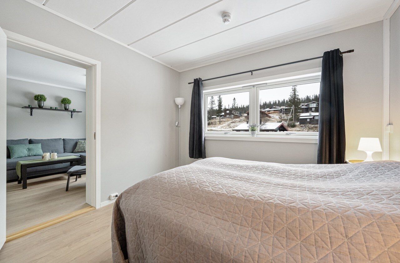 Un dormitorio con una cama grande, una ventana con cortinas, un sofá y vistas a un paisaje nevado.