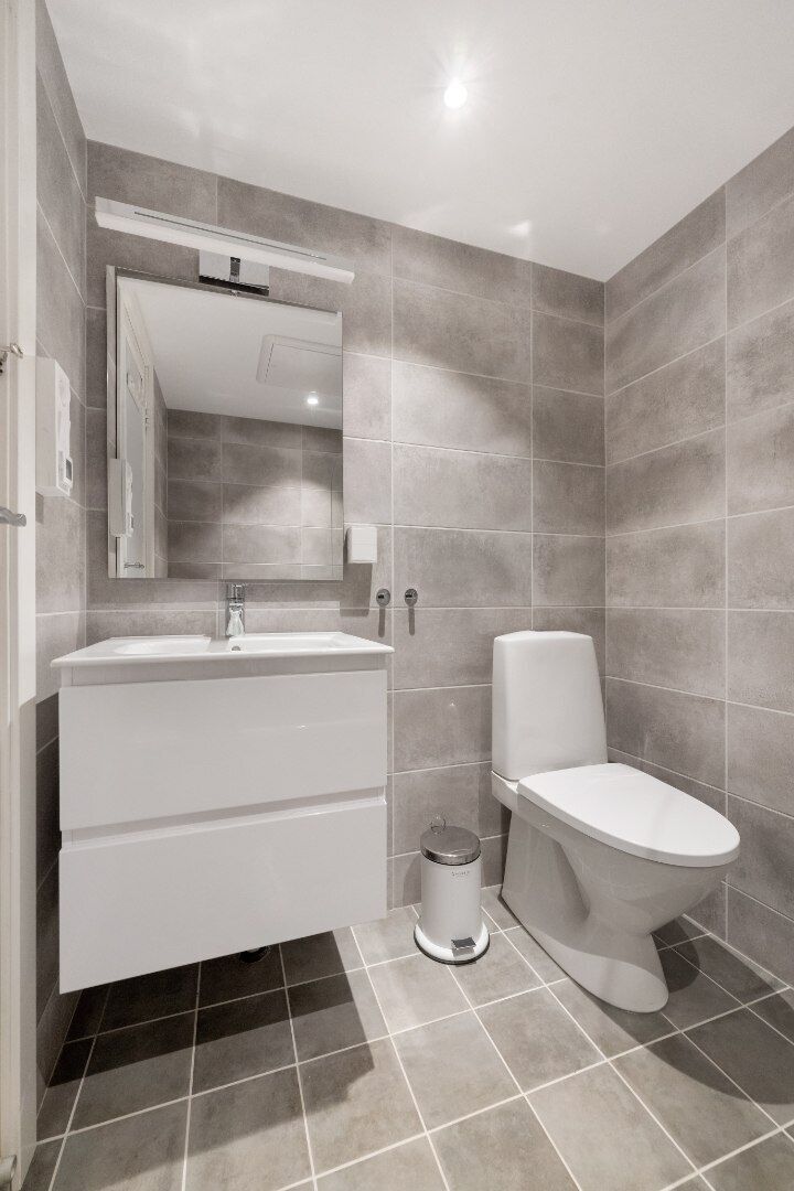 A modern bathroom with a white vanity, a toilet, and a mirror.