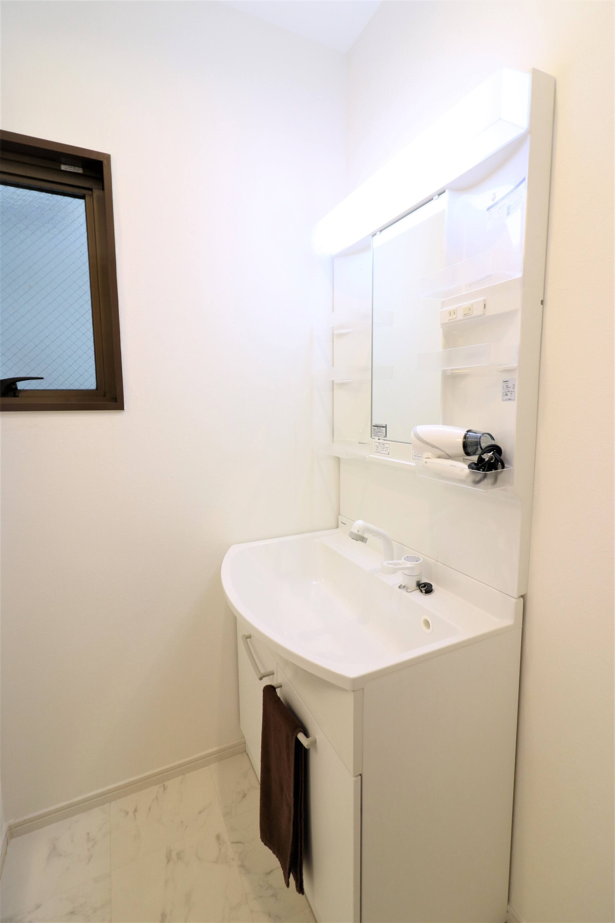Ein Badezimmer mit einem weißen Waschbecken, einem Spiegel und einem Handtuch an der Wand.