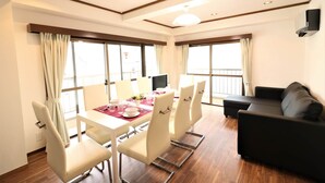 Una habitación moderna con una mesa de comedor, sillas, un sofá y ventanas amplias.