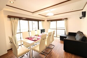 A modern room with a dining table, chairs, a sofa, and large windows. - ABC Nishigokencho (Tokyo)