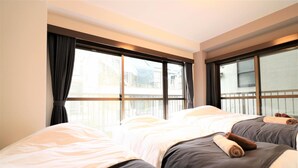 Habitación de hotel con dos camas, ventanas amplias y cortinas.