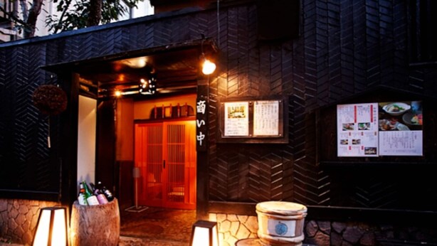 Entrada de restaurante con fachada de piedra, puerta de madera y cartel de menú.