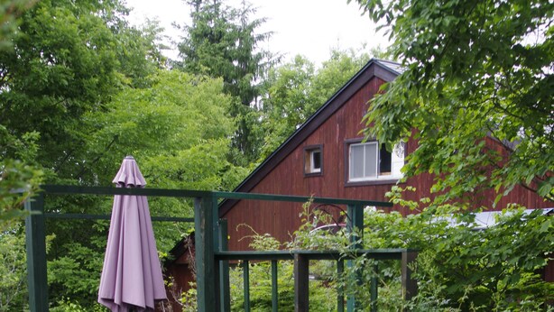 A garden area with a wooden deck, a bench, and a purple umbrella. - Gallery Hara & Guest House (Hara)