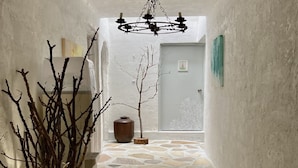 A narrow hallway with a stone floor, a chandelier, and a door with a small picture frame. - Gallery Hara & Guest House (Hara)