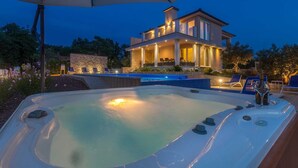 A modern house with a hot tub, outdoor seating, and a pool.