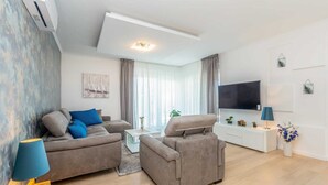 A modern living room with two sofas, a coffee table, a TV, and a small cabinet.
