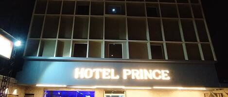 A multi-story hotel named "HOTEL PRINCE" with a grid-like facade and illuminated signage.
