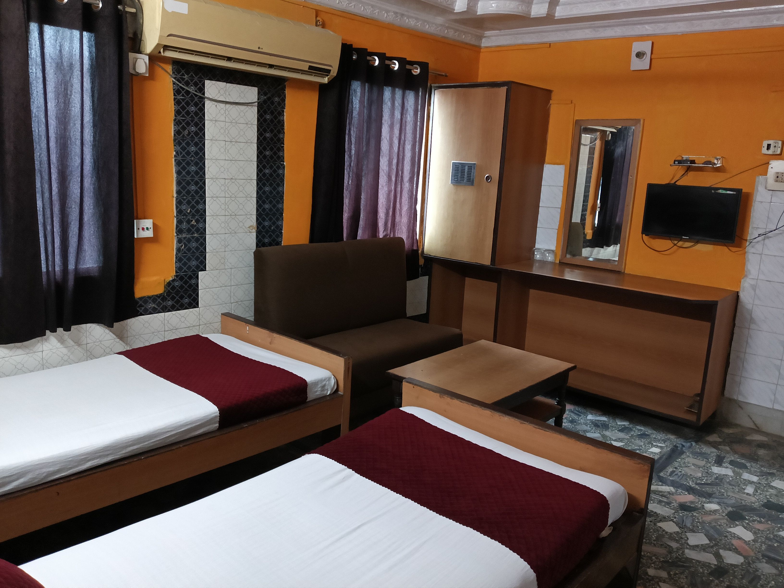 A hotel room with two beds, a desk, a chair, a wardrobe, and a television.
